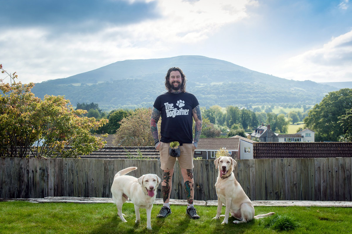 The Dogfather trainer, Rich, with two Labradors in front of the Sugar Loaf mountain in Abergavenny.